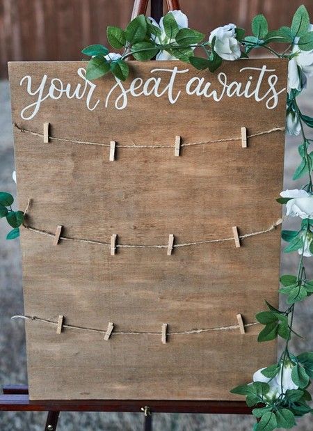 a wooden sign that says your seat awaits with flowers and greenery on it