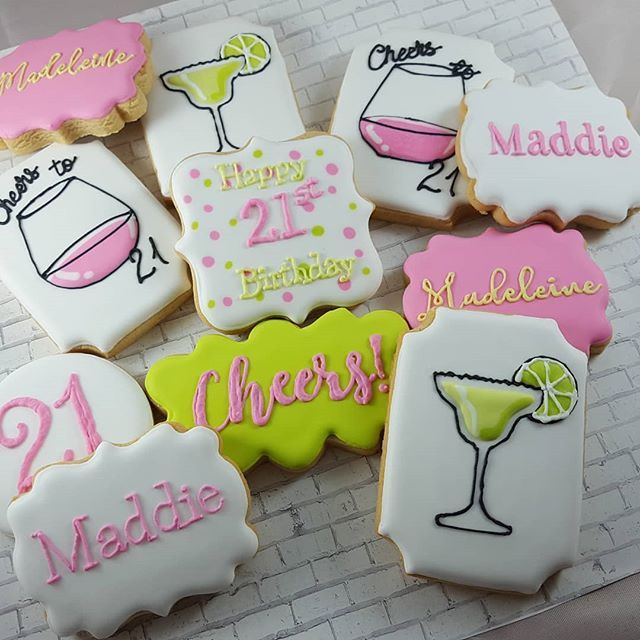 decorated cookies are arranged on a table with pink and green accents, including the words happy 21st birthday to all of them