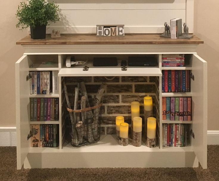 a book shelf with books, candles and other items on it in front of a wall