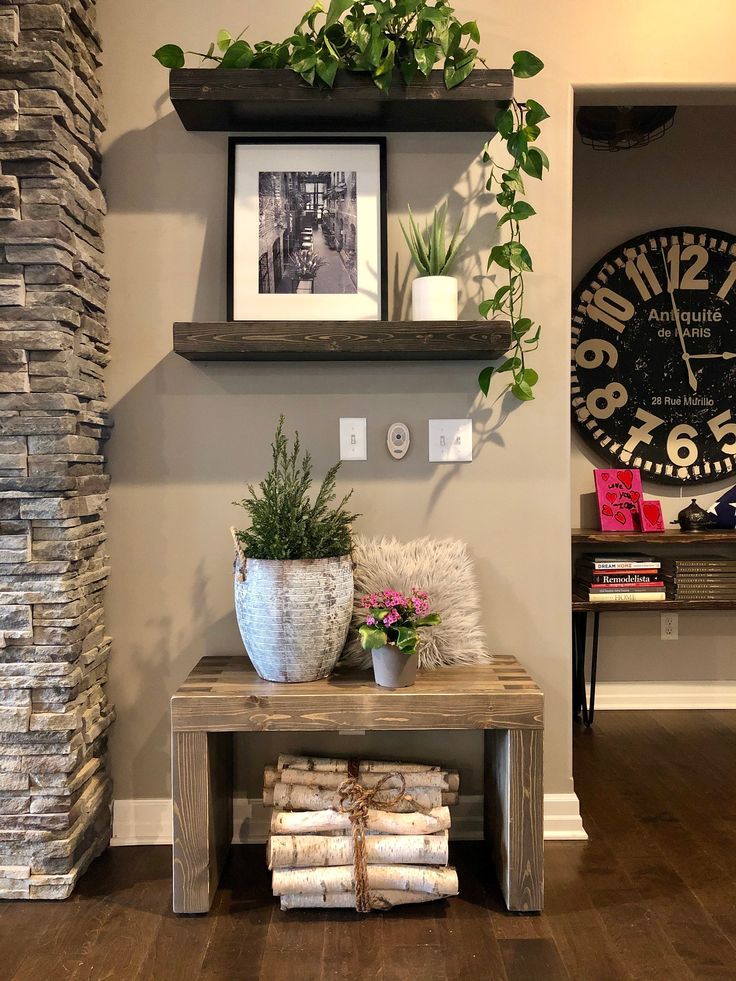 two shelves with plants and pictures on them in a living room next to a clock