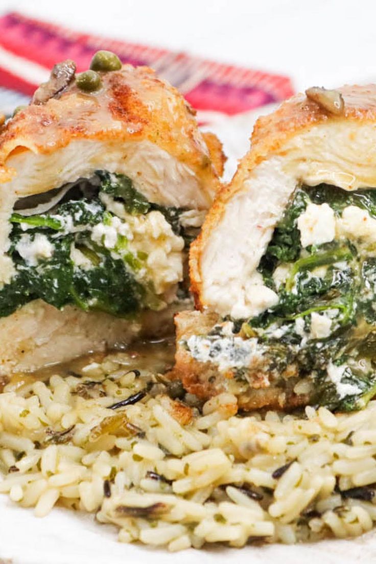 a white plate topped with chicken and spinach covered in cheese on top of rice