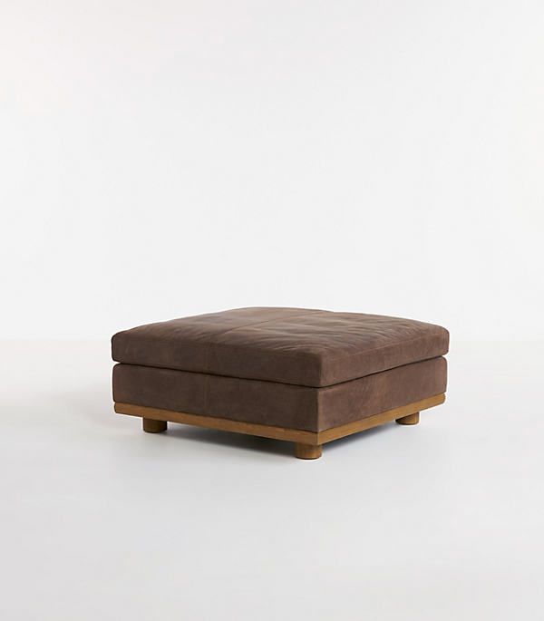 a brown ottoman sitting on top of a white floor