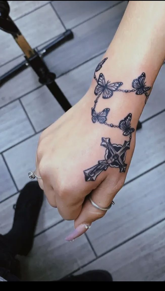 a woman's hand with butterflies on it and a cross tattooed on the wrist