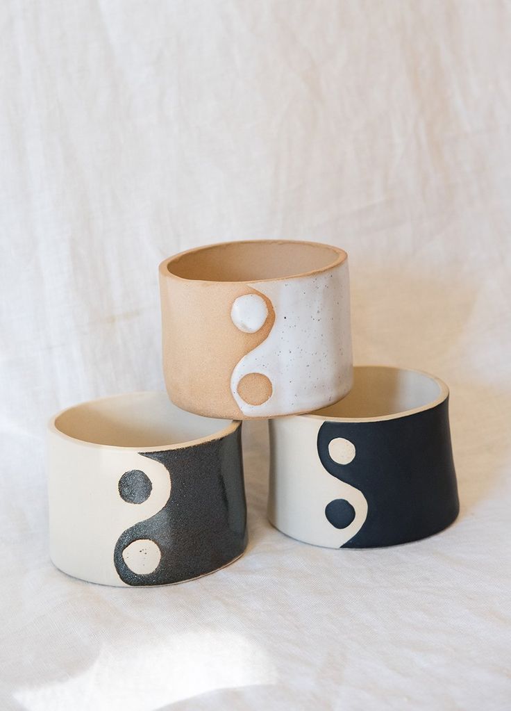 three black and white ceramic bowls sitting on top of each other in front of a white background