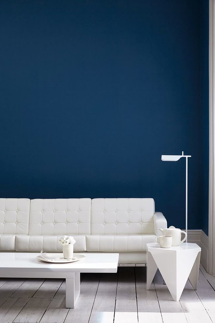 a living room with blue walls and white furniture on the floor in front of it