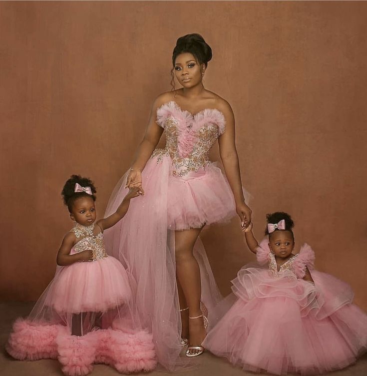 a woman and two children in pink dresses