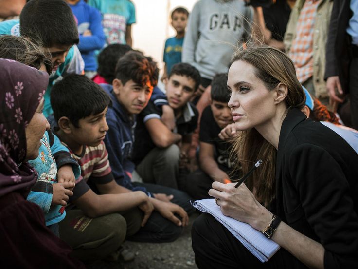 a woman sitting on the ground surrounded by other people