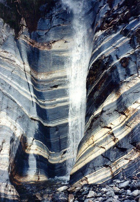 an image of a waterfall coming out of the side of a rock face with rocks below