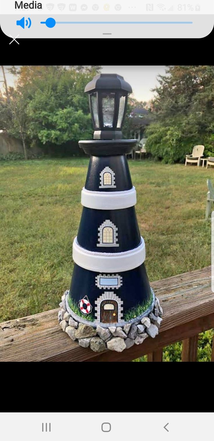 a large blue and white tower with a light on it's top sitting in front of a wooden fence