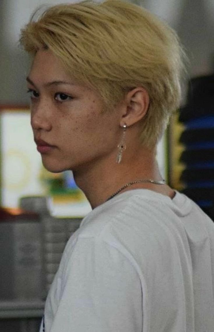 a woman with blonde hair and piercings on her ear looking off to the side