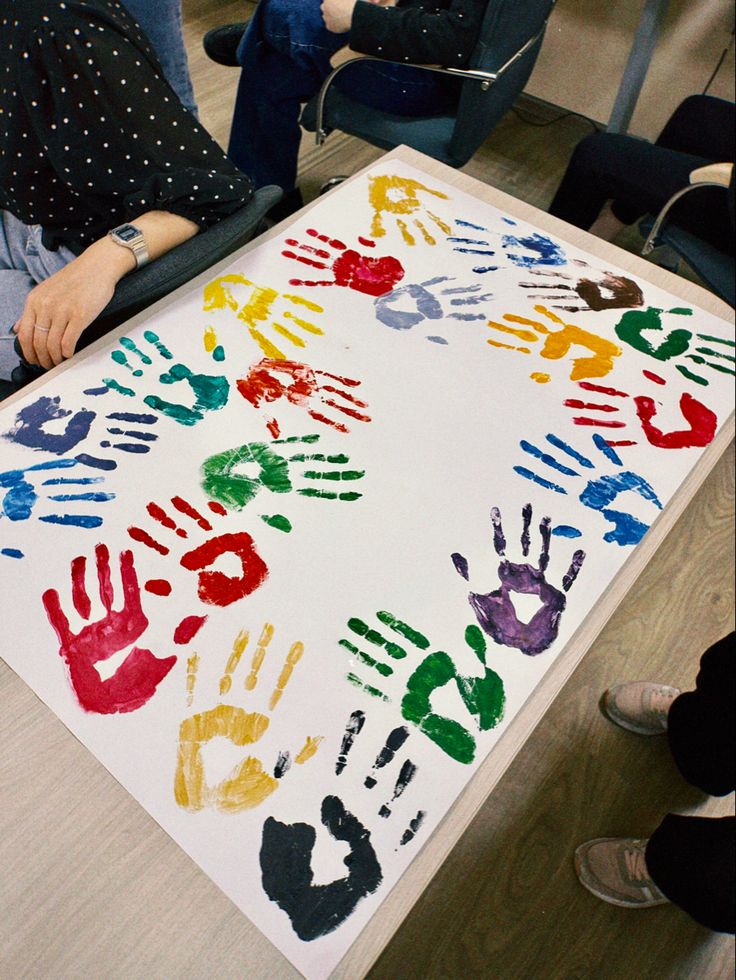 a group of people sitting around a table with hand prints on it