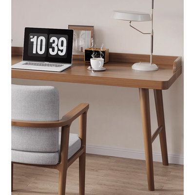 a laptop computer sitting on top of a wooden desk next to a lamp and chair