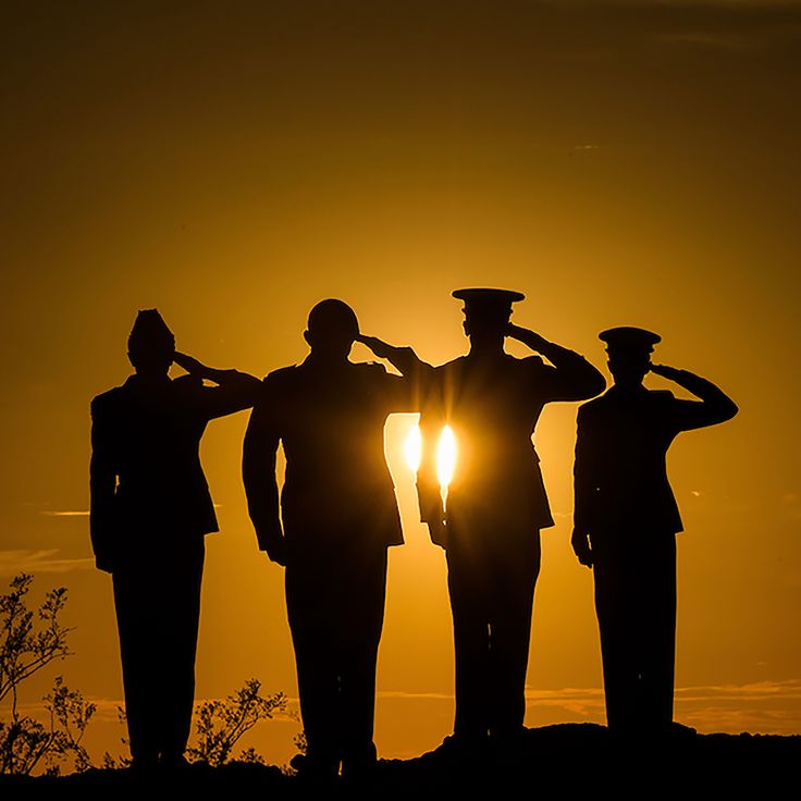 the silhouettes of three men in uniforms are shown at sunset with the sun behind them