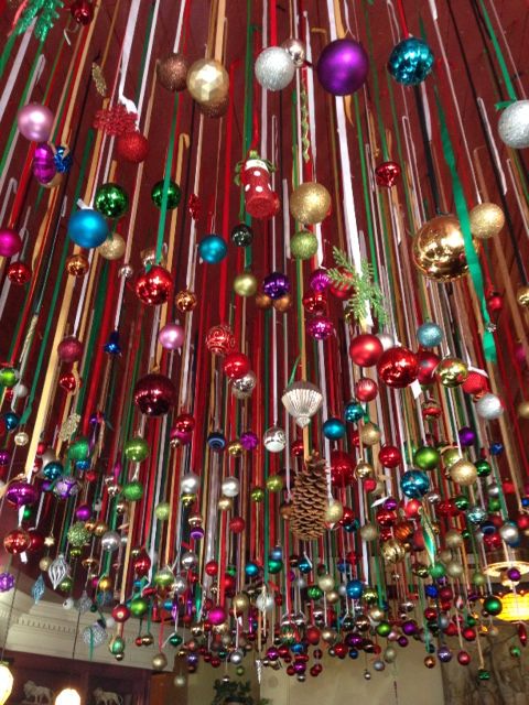 a room filled with lots of colorful christmas ornaments hanging from the ceiling and lights on the ceiling