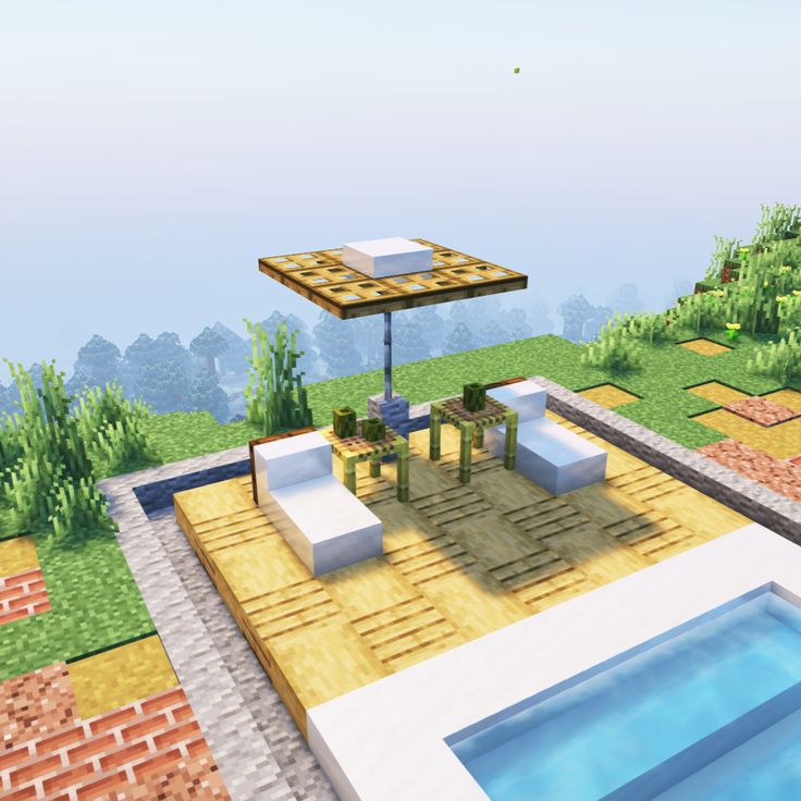 a small patio with tables and chairs next to a pool in the middle of a field