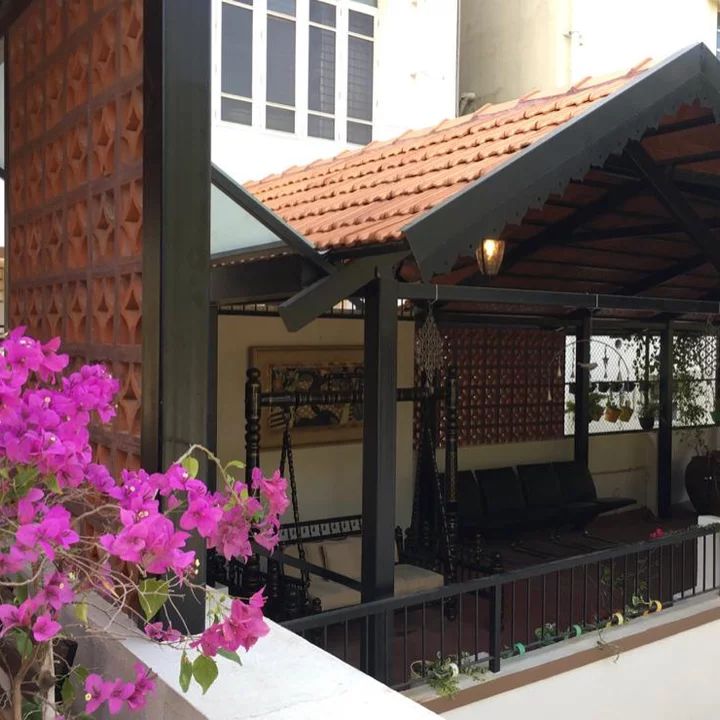 an outdoor covered patio with purple flowers in the foreground and a building behind it