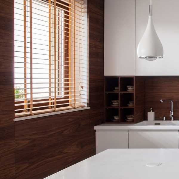 a kitchen with white counter tops and wooden blinds