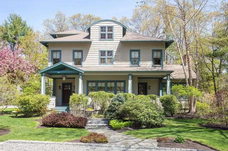 a house that is in the middle of some trees and grass with bushes around it