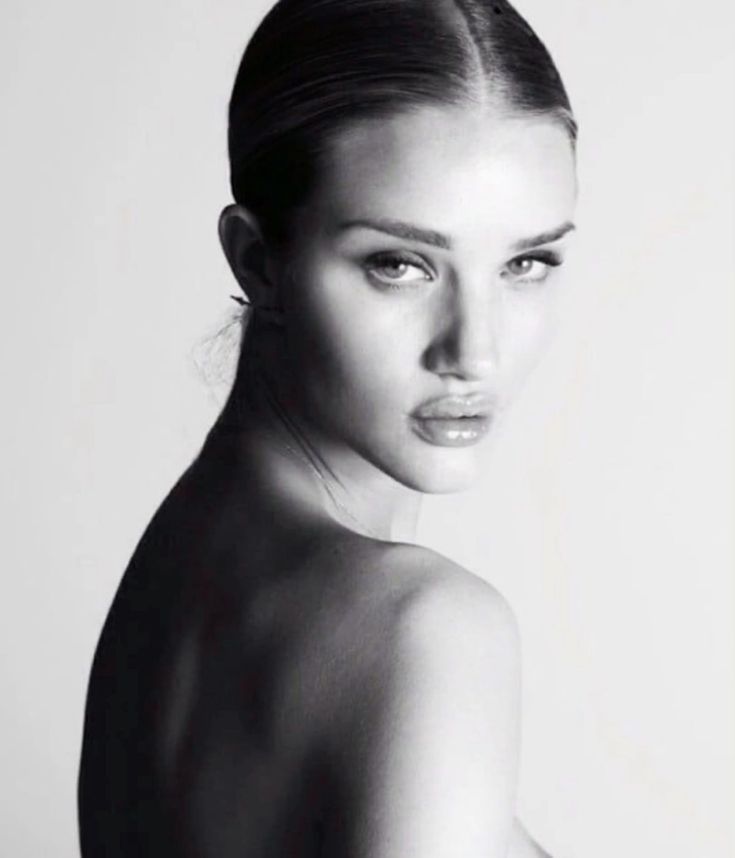 a black and white photo of a woman's face with her hair pulled back