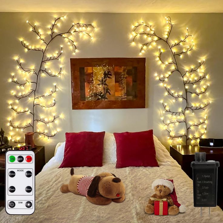 two teddy bears laying on a bed with christmas lights in the background and a painting above it