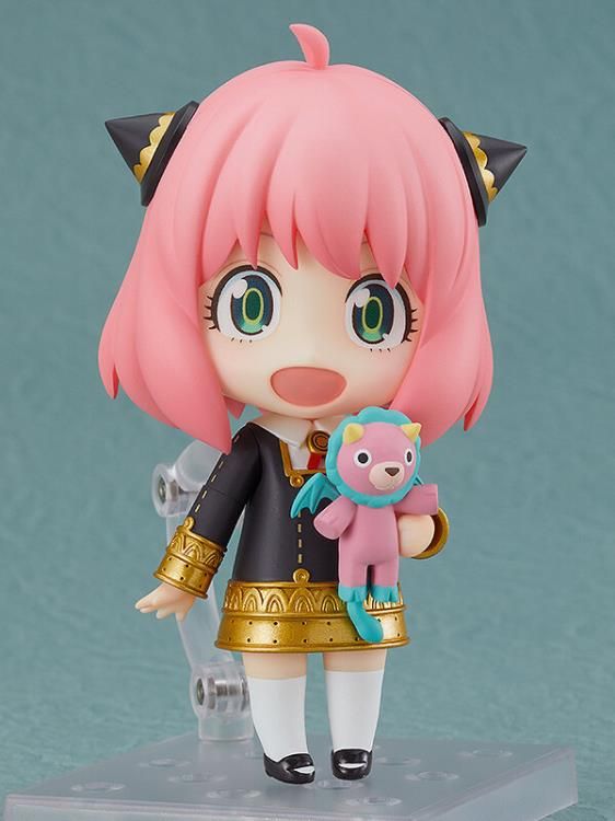 a doll with pink hair is holding a small teddy bear on a clear stand against a blue background