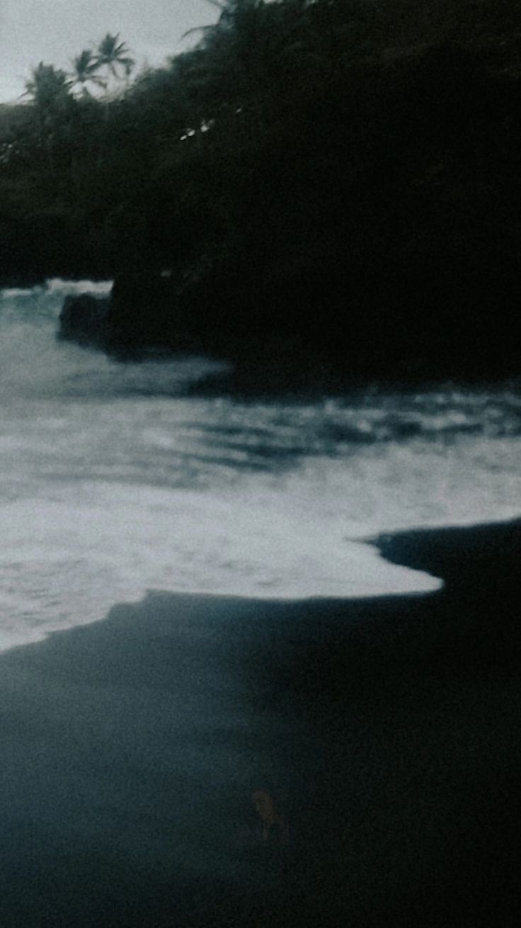 a person standing on the beach holding a surfboard in their hand and looking out at the ocean