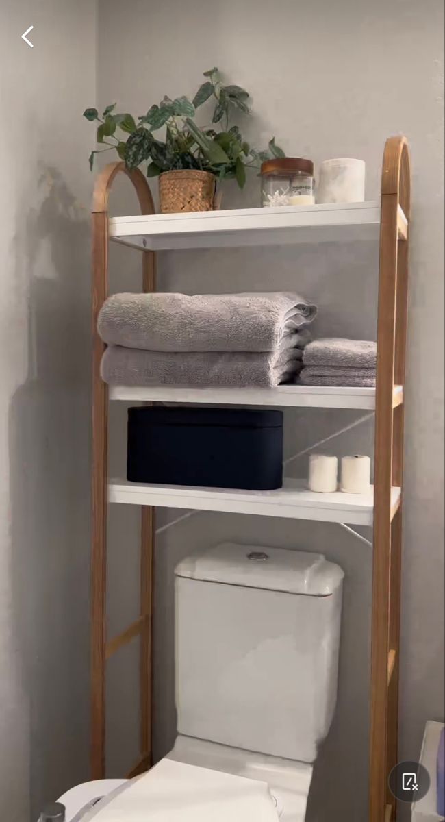 a white toilet sitting next to a shelf filled with towels