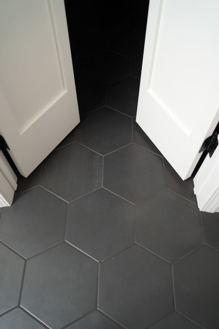 two white doors open on a black tiled floor