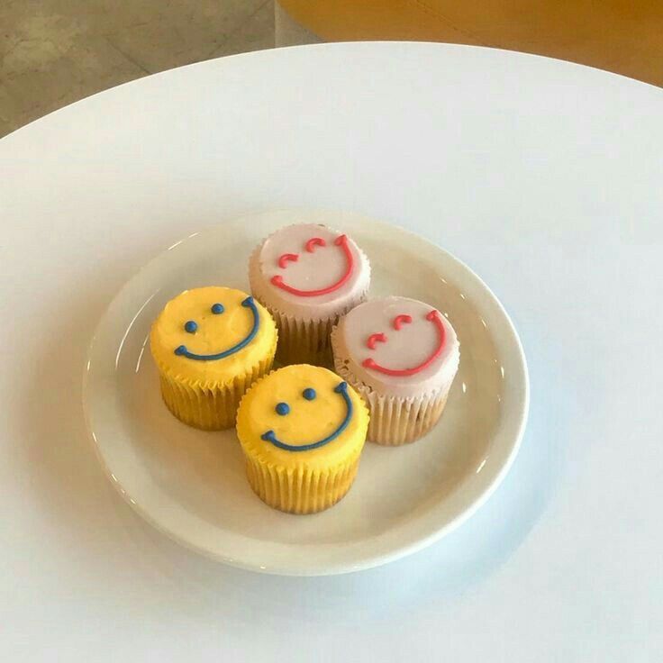 three cupcakes on a plate with smiley faces