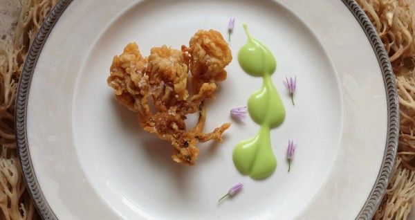 two desserts on a white plate with green icing and purple flower petals in the middle