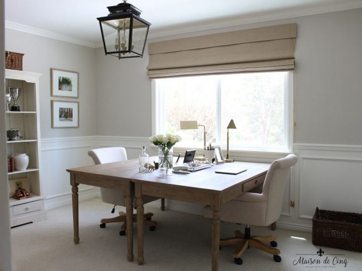 a table with two chairs and a lamp hanging from the ceiling in front of a window