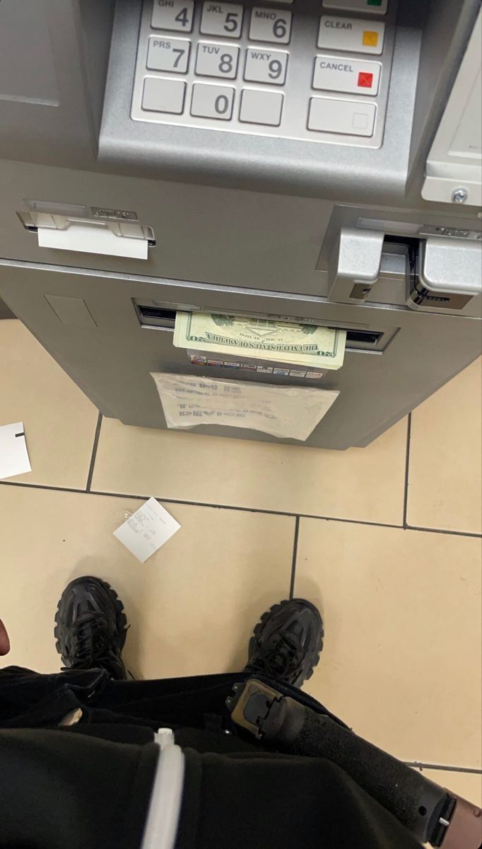 a person standing in front of an atm machine with their feet up on the ground