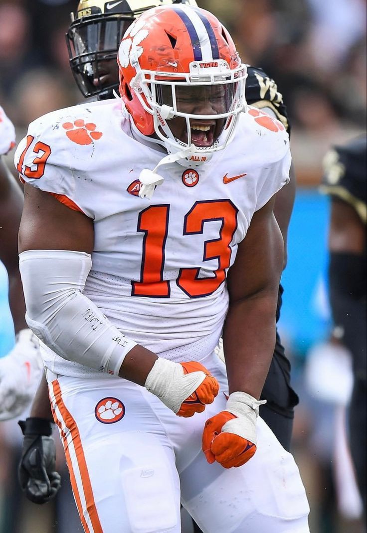 an orange and white football player with his hands on his hips while holding the ball