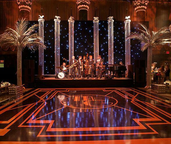 a stage set up for an event with lights and decorations on the floor, surrounded by palm trees