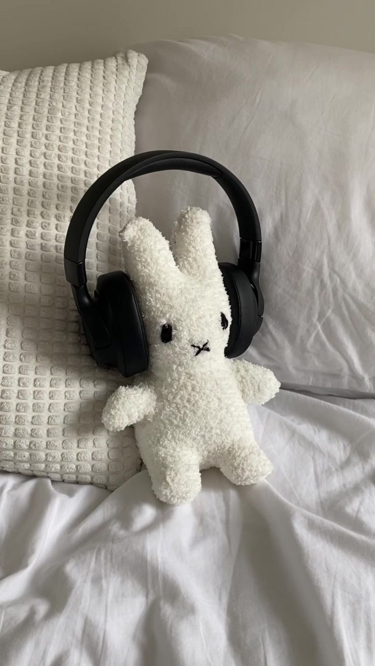 a stuffed animal with headphones on top of a bed