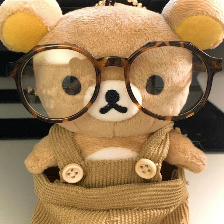 a brown teddy bear wearing glasses on top of a table