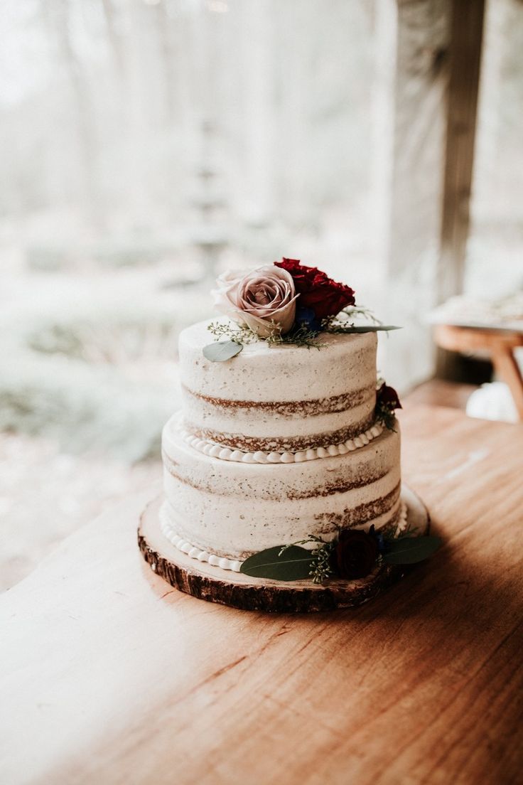 a three tiered cake sitting on top of a wooden table next to a window