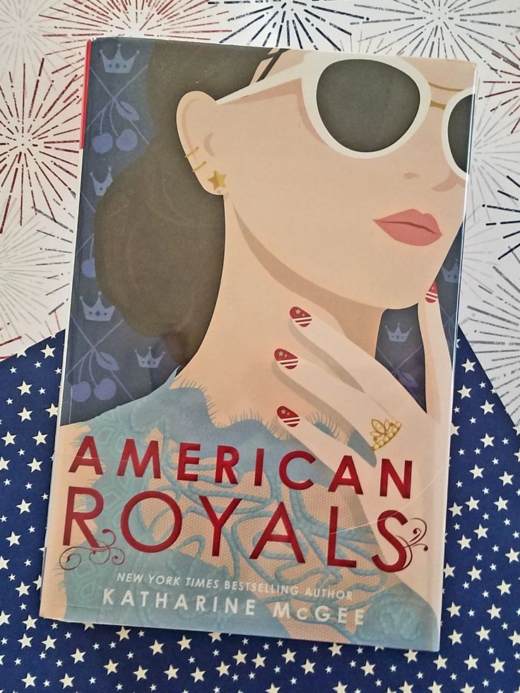 an american royals book sitting on top of a blue and white tablecloth with fireworks in the background