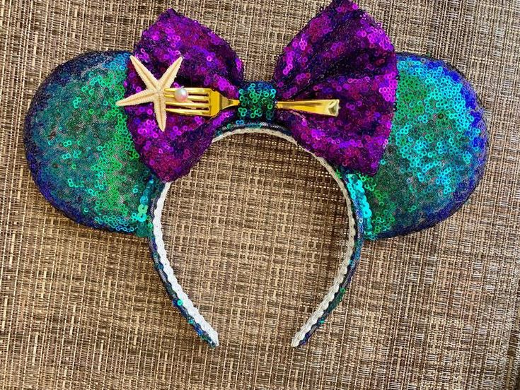 a purple and green mouse ears with a starfish on the top, sitting on a brown surface