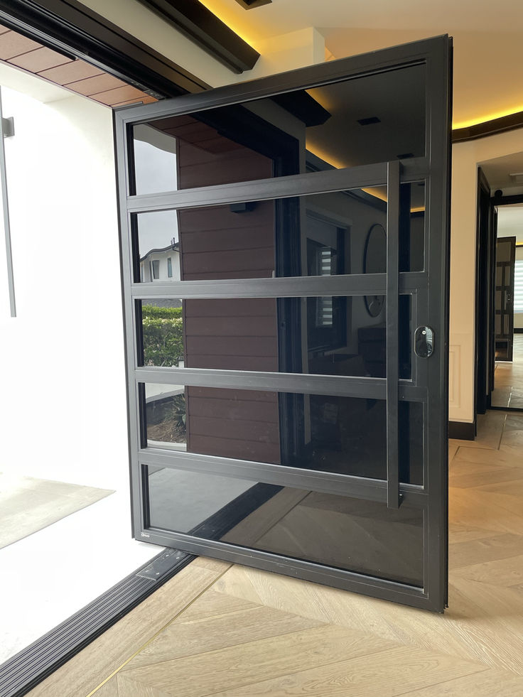 an open glass door in the middle of a room with wood flooring and white walls