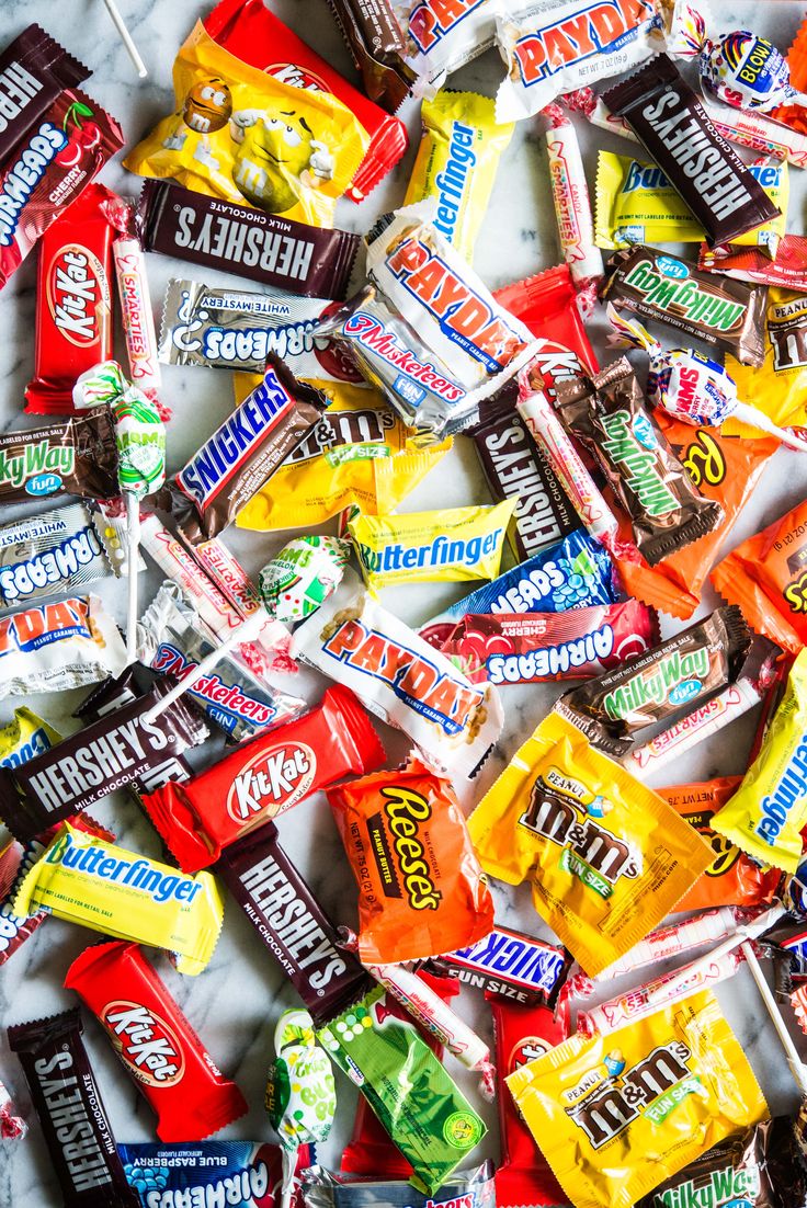 a pile of assorted candy bars sitting on top of a white countertop next to each other