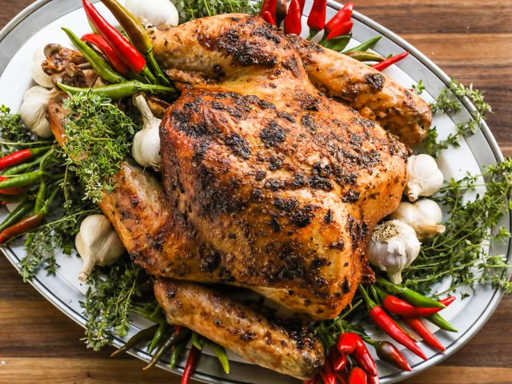 a white plate topped with chicken and veggies on top of a wooden table