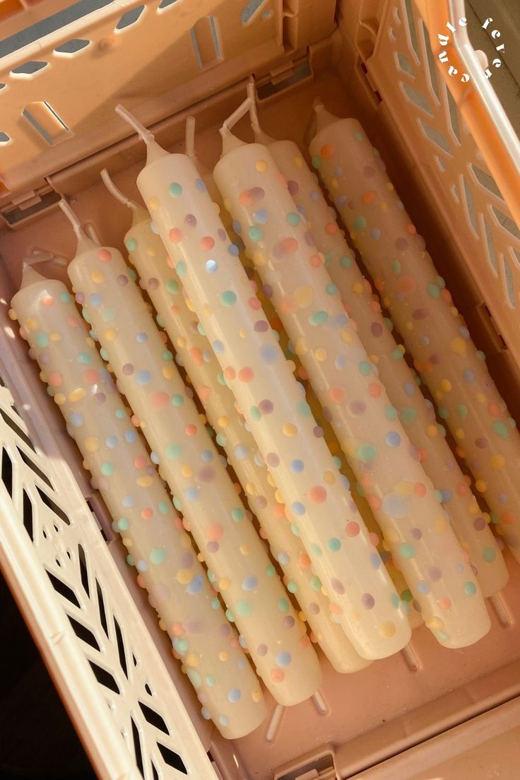 four candles are lined up in a pink box with white and blue polka dots on them