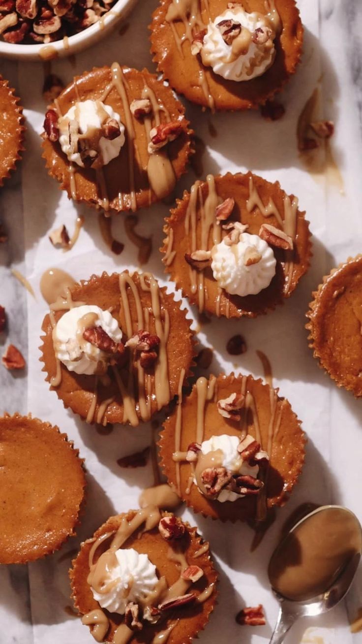 several cupcakes with pecans and whipped cream on top are sitting next to a bowl of nuts