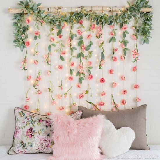 a bed topped with pillows covered in pink flowers and greenery next to a white brick wall