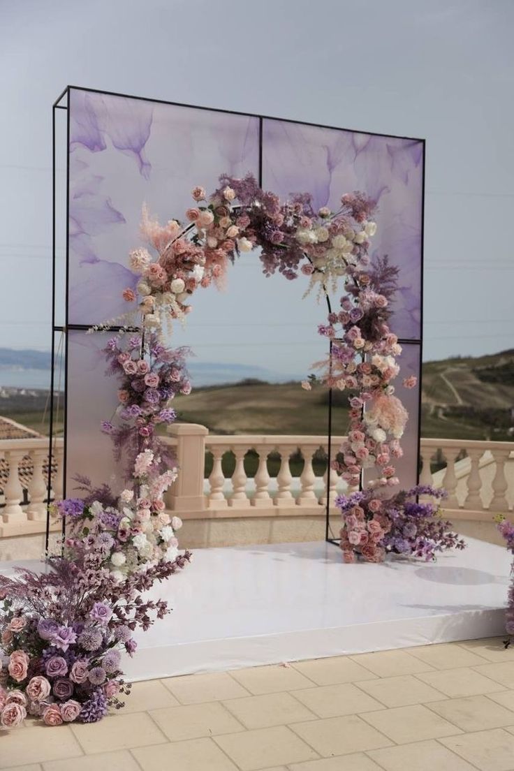 an outdoor ceremony setup with purple flowers and greenery in front of a large mirror