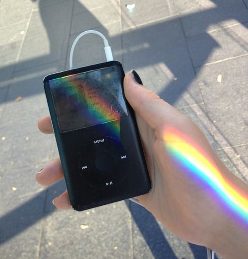 a hand holding an mp3 player with a rainbow painted on the screen and earphones attached to it