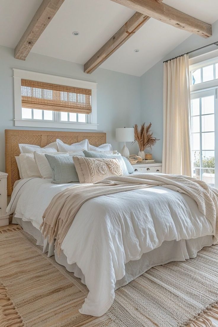 a large bed in a bedroom next to a window with wooden beams on the ceiling