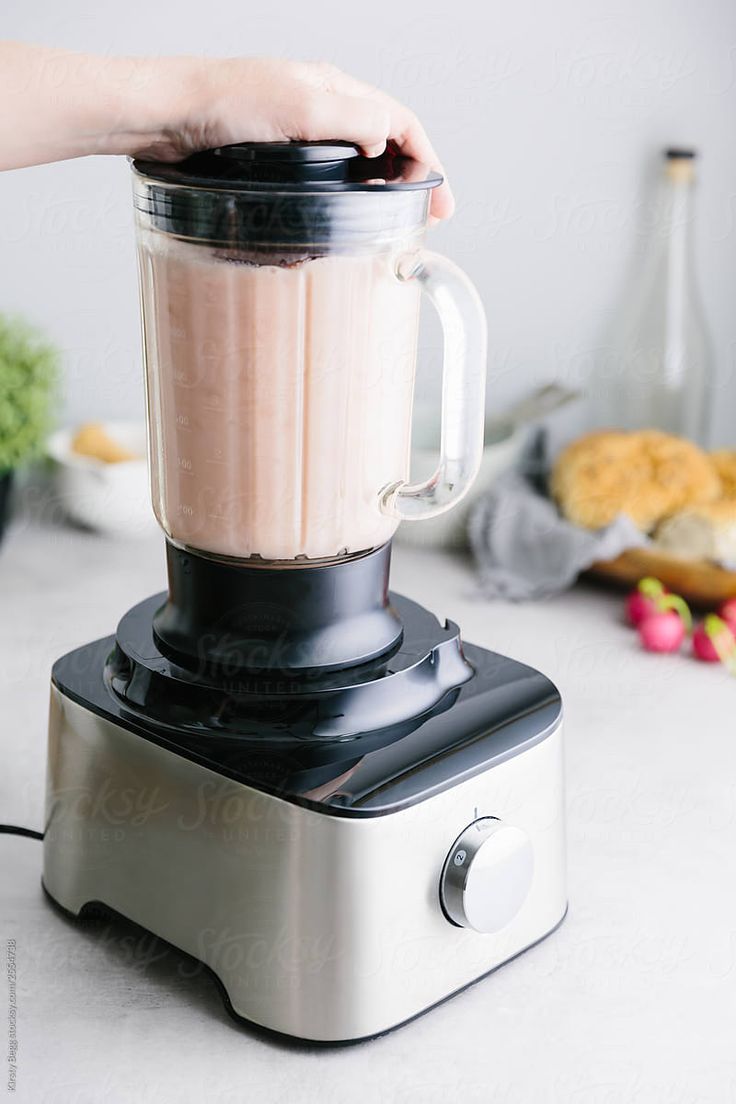 a person is using a blender to make something brown and pink in the kitchen