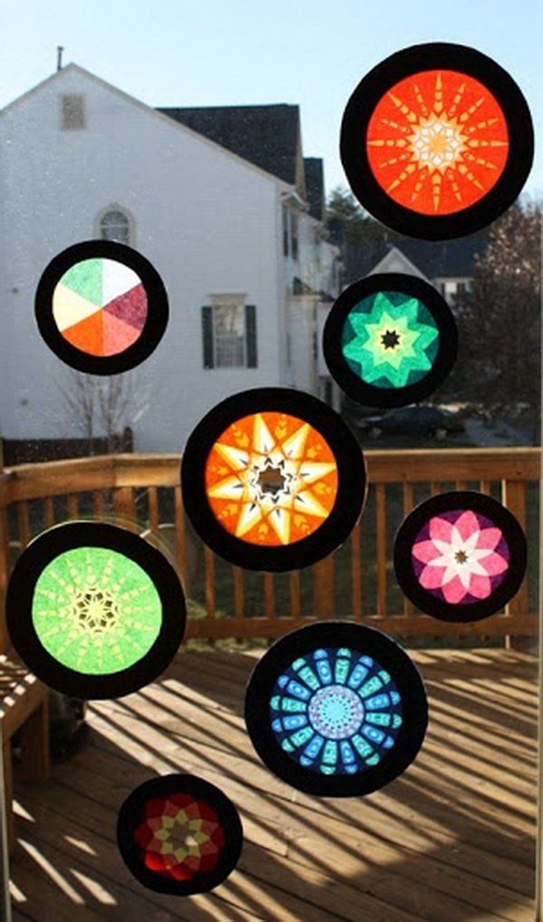 a group of different colored lights hanging from a wooden deck next to a white house